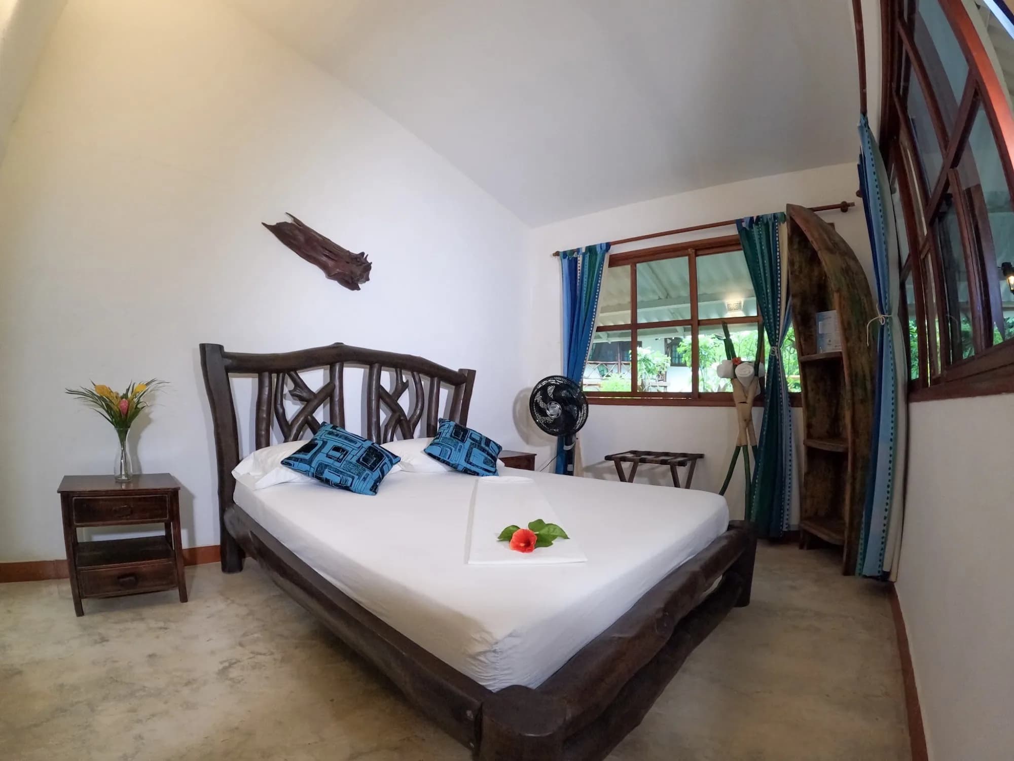 Habitación Arhuaco con cabecero de madera tallada y textiles azules, en la Casa Indígena