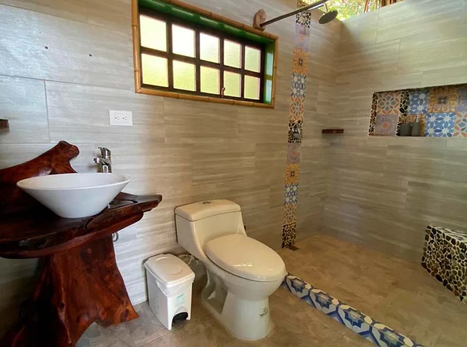 Baño privado de Casa del Mar con lavamanos de piedra tallada y ventana de madera