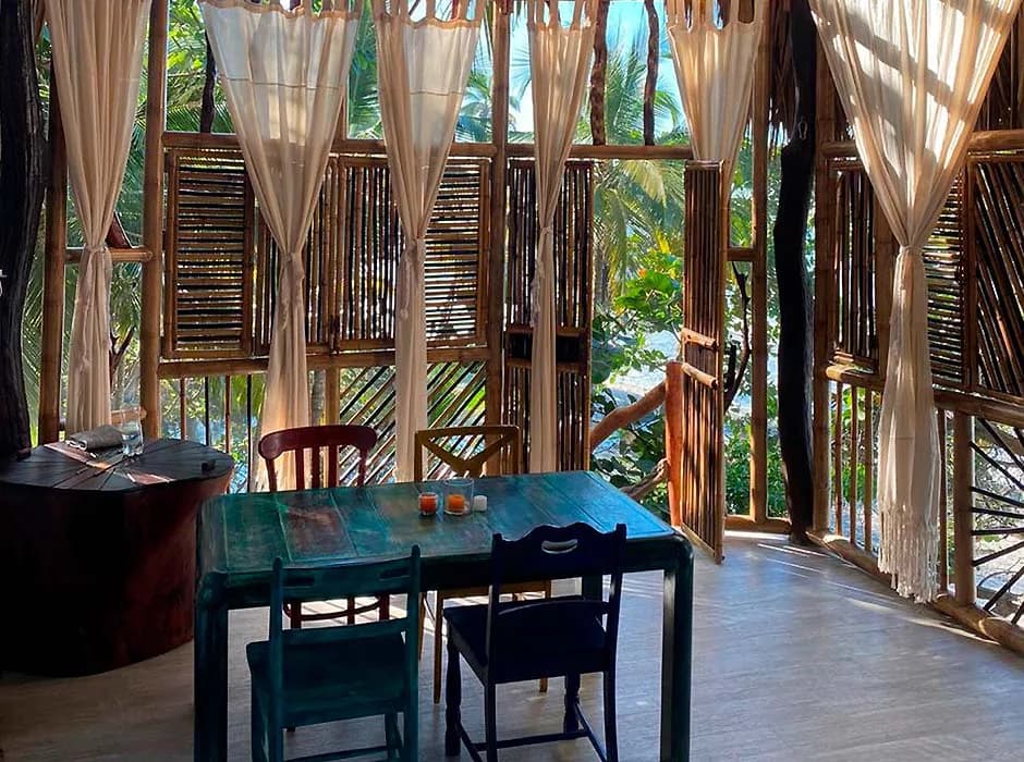 Comedor de Casa del Mar con mesa de colores y ventanales abiertos a la vegetación