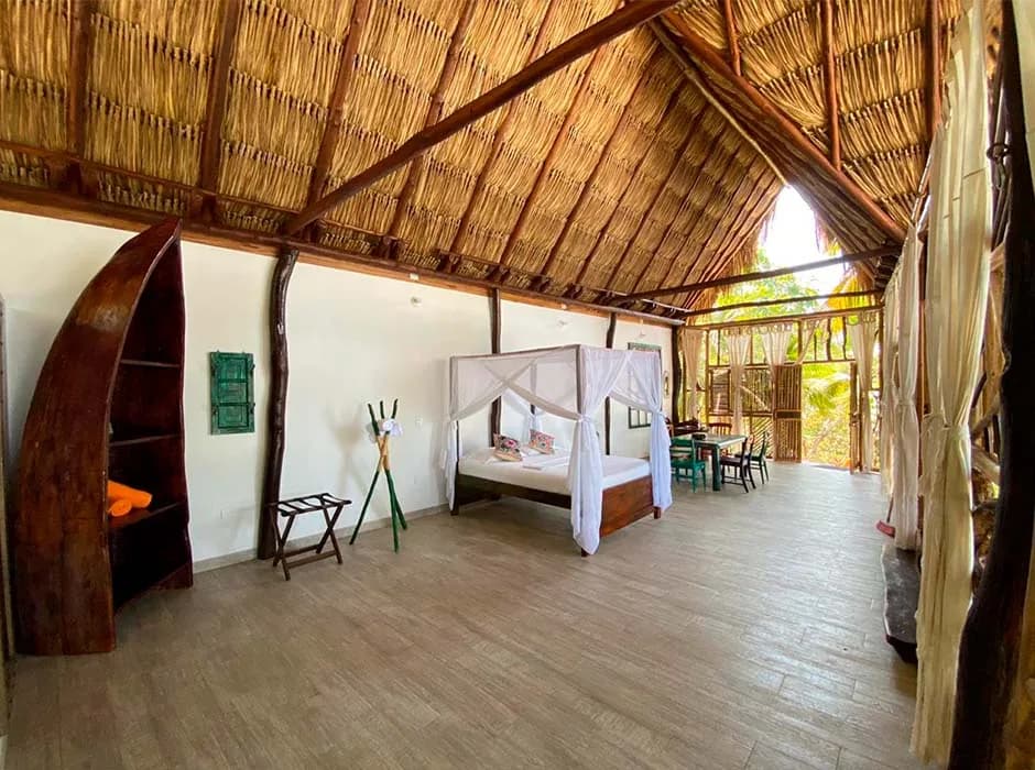 Habitación de Casa del Mar con cama de dosel y mosquitero bajo el techo de palma