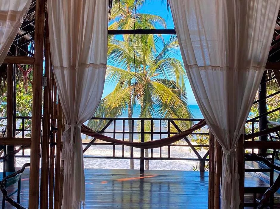 El mar Caribe enmarcado entre las cortinas y la estructura de madera de la cabaña