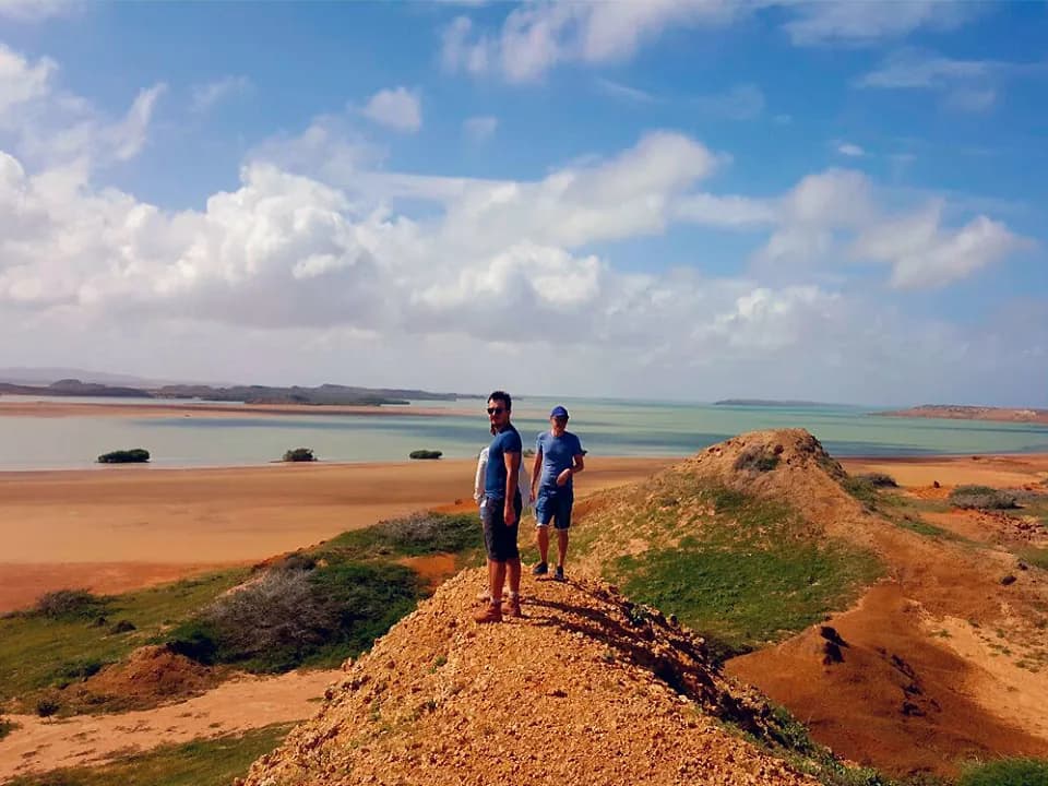 Viajeros sobre una duna roja frente al mar, en la Alta Guajira