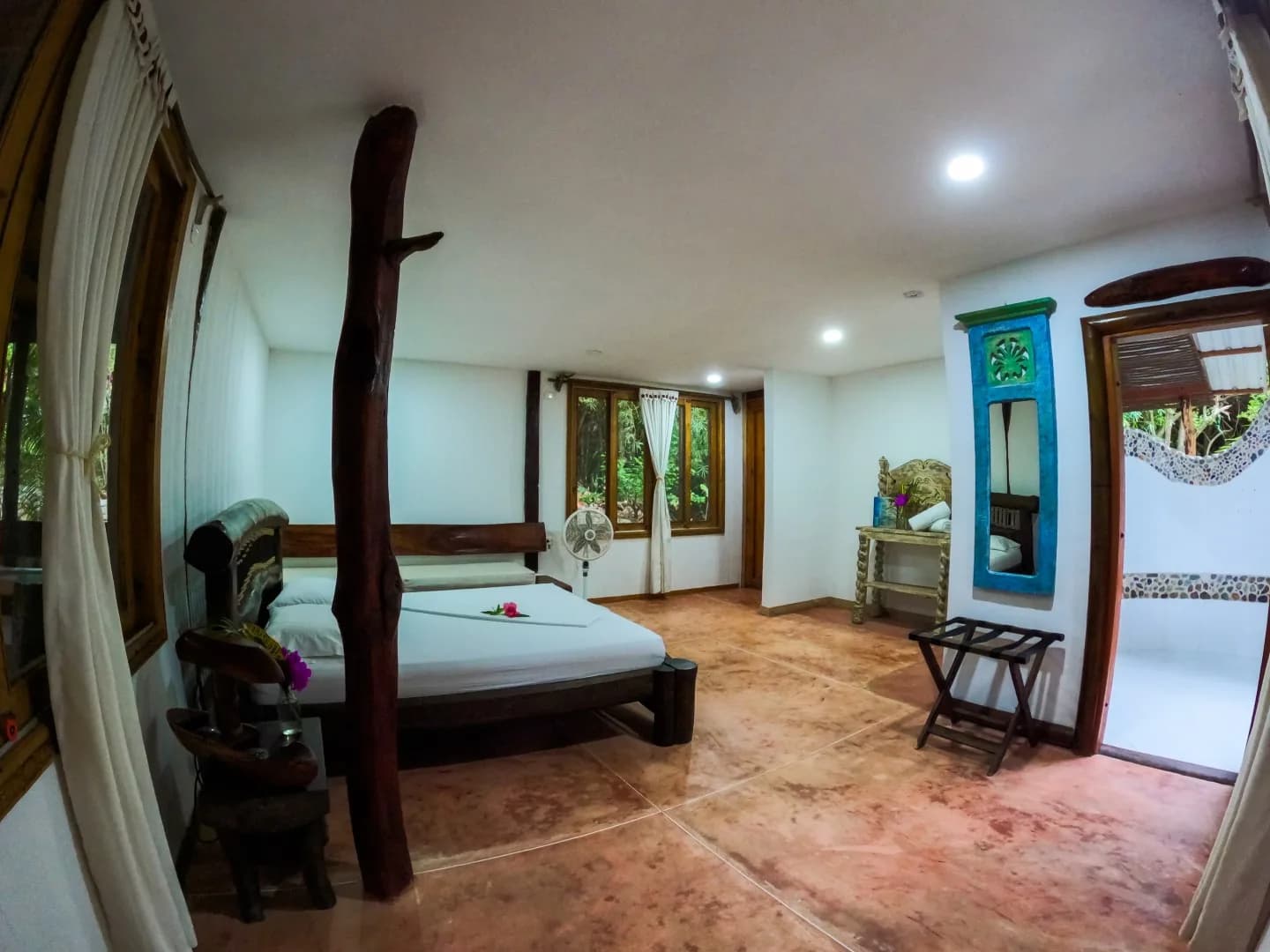 Habitación Higuerón con cama de madera y ventanales al bosque en la Cabaña Aluna