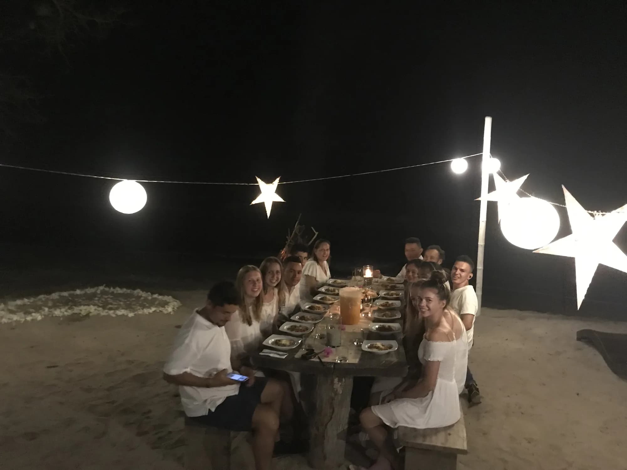 Mesa larga montada en el jardín, con luces colgantes bajo las estrellas