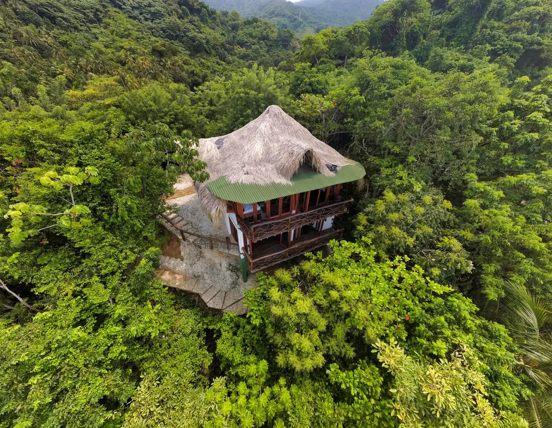 Vista aérea de la cabaña Morro Paraíso con techo de palma rodeada de selva sobre el mar