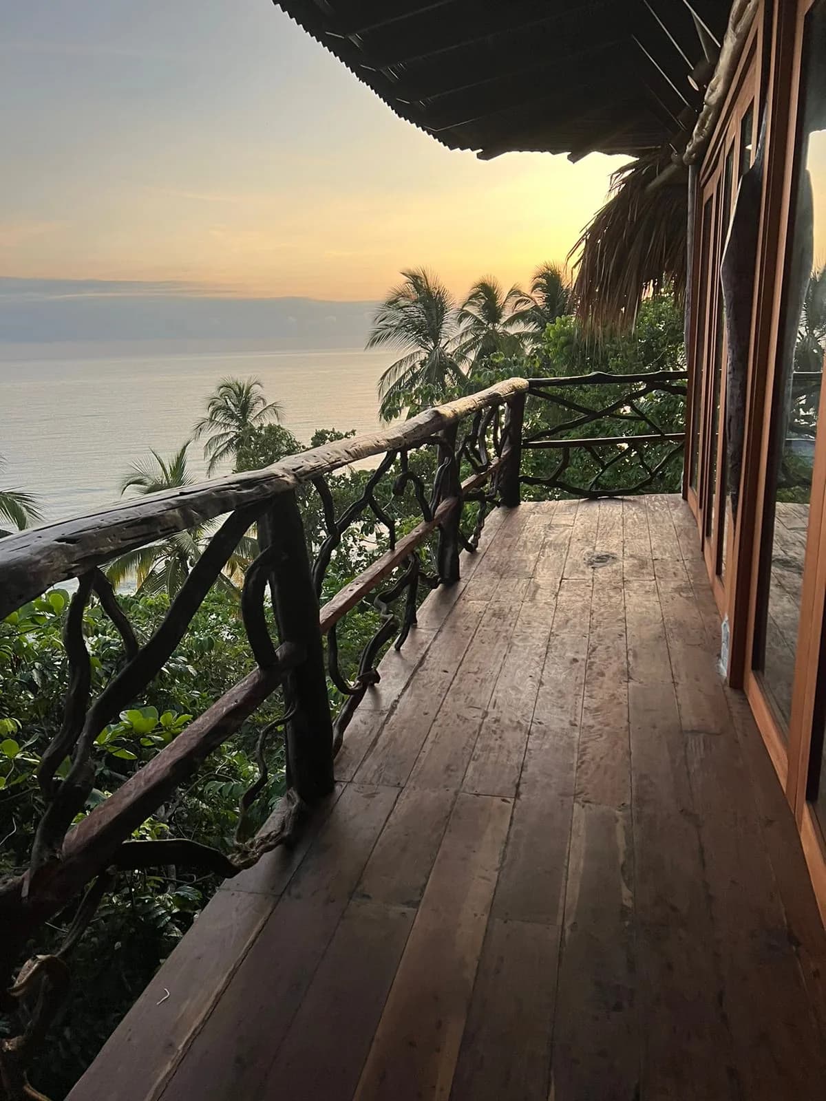 Balcón de madera de Morro Paraíso con barandas rústicas y vista a la selva y al mar